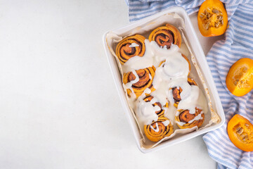 Homemade sweet autumn pumpkin cinnamon swirled bun rolls, pumpkin cinnabons with pecan nuts, cinnamon and creamy cheese icing
