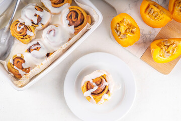 Homemade sweet autumn pumpkin cinnamon swirled bun rolls, pumpkin cinnabons with pecan nuts, cinnamon and creamy cheese icing