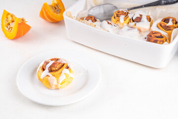 Homemade sweet autumn pumpkin cinnamon swirled bun rolls, pumpkin cinnabons with pecan nuts, cinnamon and creamy cheese icing