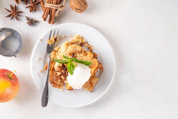 Apple Crumble Dessert, crisp cobbler with Ice Cream, crumble pie with crunchy dough topping in baking dish and plate, with ice cream scoop on white kitchen table