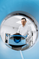 In a bright diagnostic center, a young man undergoes a CT or MRI scan using modern equipment. This...