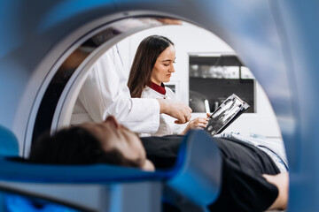 A patient undergoes an MRI or CT scan as doctors review images in a modern diagnostic center. This...