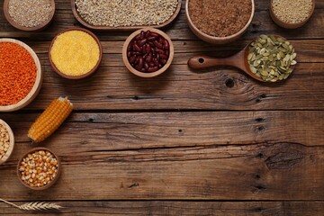 Different types of cereals, seeds and legumes on wooden table, flat lay. Space for text