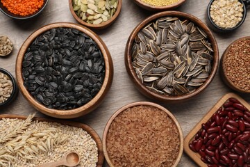 Different types of cereals, seeds and legumes on wooden table, flat lay