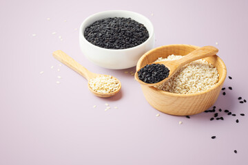 Sesame seeds in bowl, white and black sesame on pink background