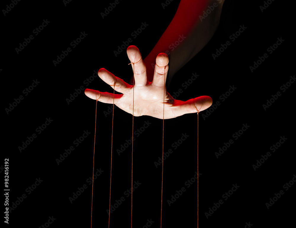 Wall mural Puppeteer's hands with strings on each finger on black background.