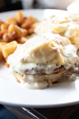 grilled homemade biscuit topped with two sausage patties, two scrambled eggs bacon cheddar cheese and sausage gravy served with home fries