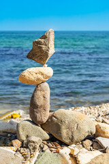 Balanced stone sculpture, rocky shore, tranquil sea