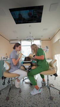 Blonde Woman Dentist with Assistant Treat Teeth Female Patient with Special Instrument. Treatment Caries and Plaque in Dental Clinic. Concept of Medicine and Healthcare. Vertical Video. Slow Motion.