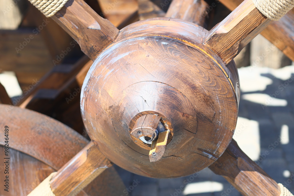 Poster a detailed view of a wooden wheel with ropes wrapped around it, suitable for use in historical or ru