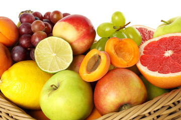 Many different fresh fruits in wicker basket isolated on white