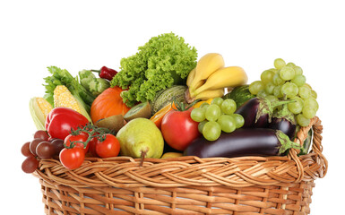 Different fresh fruits and vegetables in wicker basket isolated on white