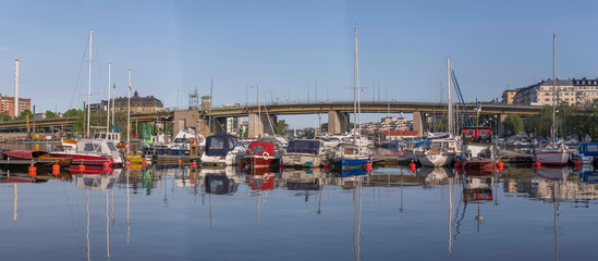 Panorama, the bay &Aring;rstaviken, a jetty with day curiser and sailing boats at the bridge Liljeholmsbron, sunny summer morning in Stockholm