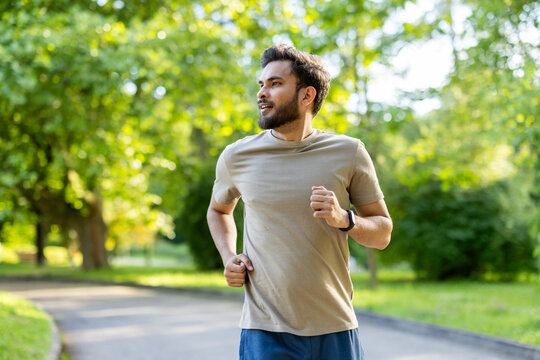 Man jogging in the park enjoying active outdoor exercise under sunny skies wearing fitness tracker