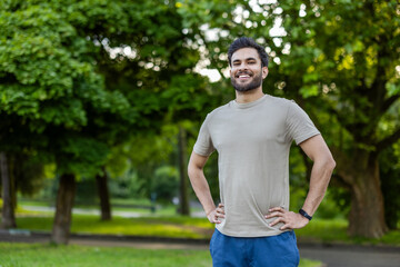 Man in park smiling confidently with hands on hips enjoying outdoor fitness and exercise