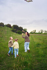 Obraz premium two little sisters and mother run and launch a kite in a field