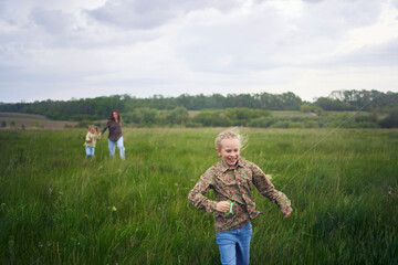 two little sisters and mother run and launch a kite in a field