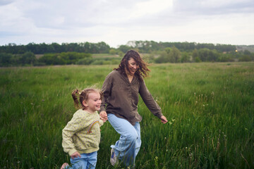 Fototapeta premium two little sisters and mother run and launch a kite in a field