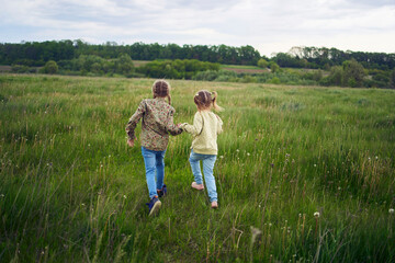 beautiful blonde sisters play with a dandelion in the field