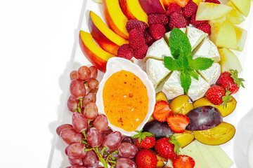 Assorted cheese plate with fruits and sauces isolated on white background. Vegan snacks concept