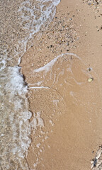 A detailed view of a sandy beach and a breaking wave