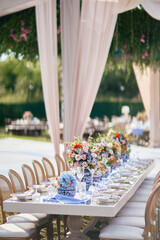 A beautifully decorated outdoor wedding reception with long tables adorned with vibrant floral...