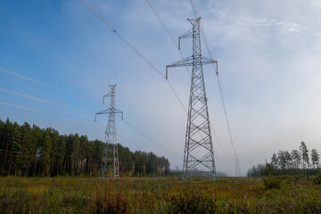Electric transmission lines  in the foggy morning autumn forest. Power lines.