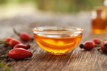A bowl of rose hip seed oil with fresh rosehips