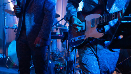 Close up of guitarist in blue suit playing during a concert at night