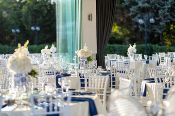 Elegant Outdoor Wedding Reception with White and Blue Floral Centerpieces, Silver Chairs, and...