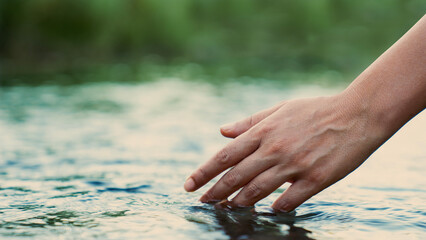 A female hand touching the river water	