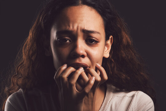 Sad woman, portrait or fear with trauma for abuse, anxiety or stress in mental illness on a dark studio background. Scared, female person or nervous victim with worry, afraid or feeling in isolation