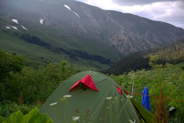A tourist tent stands in the grass in the mountains