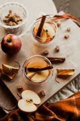 apple tea in glass cups with red apple slices and cinnamon stick, autumn tea, autumn drink, tea with brown cane sugar, autumn composition, fruit tea