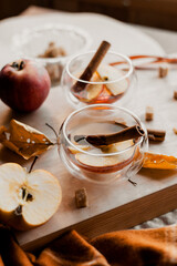 apple tea in glass cups with red apple slices and cinnamon stick, autumn tea, autumn drink, tea with brown cane sugar, autumn composition, fruit tea