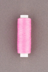 Pink thread spool close-up macro flat lay top view.