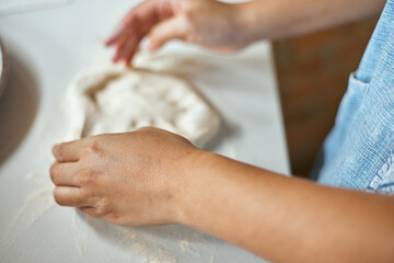 Hands knead dough to make a pizza