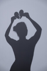 Silhouette of a girl holding a heart in her hands.