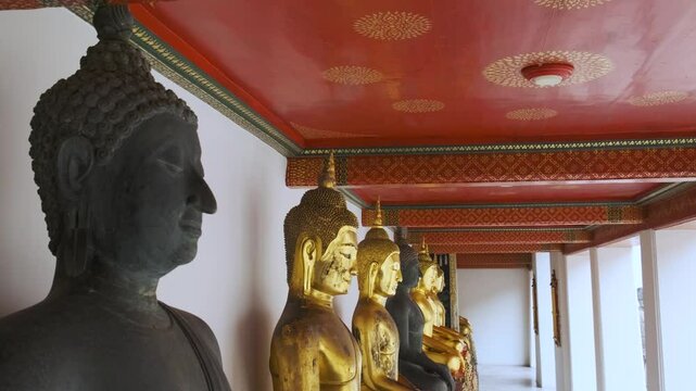 Black Buddha in a row of golden Buddha statues in Wat Pho Temple Complex in Bangkok city, Thailand, Asia. Temple of the Reclining Buddha. Popular travel landmark