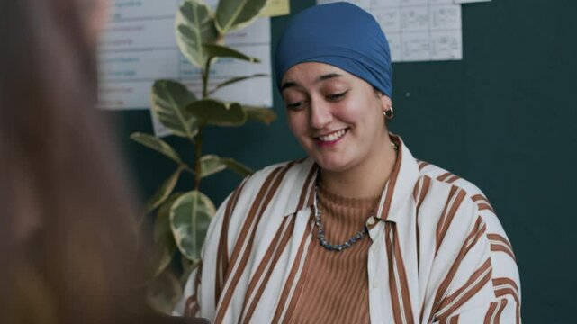 Waist up of young Muslim woman using sticky notes while learning English together with other students in modern classroom
