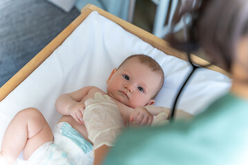 Infant baby at medical appointment doctor with stethoscope examining child