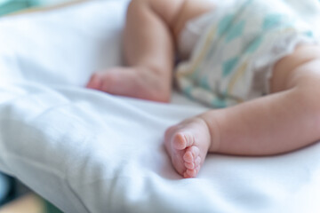 Unrecognizable infant child wearing diaper baby's feet on bed, copy space