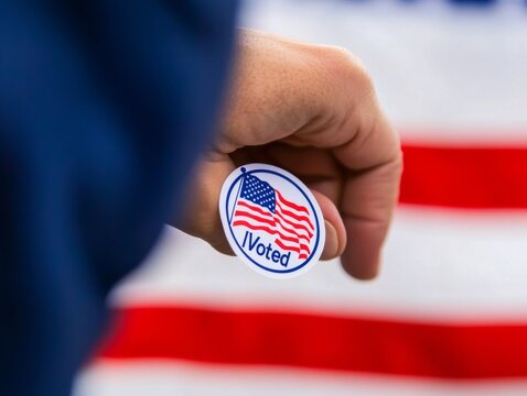 Hand Proudly Holding an I Voted Sticker Near a Waving American Flag