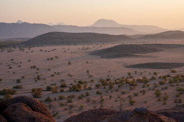A view across the mountains and desert of Twyfelfontein, Namibia showing the layers of terrain in the haze as the sun sets