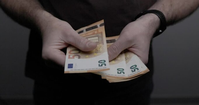 Man is counting a stack of fifty euro banknotes