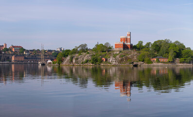 Fototapeta premium Panorama, old castle in the island Kastellholmen, sailing and commuter boats, the old town, a calm sunny summer morning in Stockholm