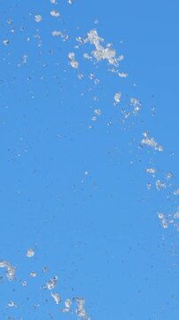 Splashes of water against a background of a cloudless blue sky. Slow motion.
