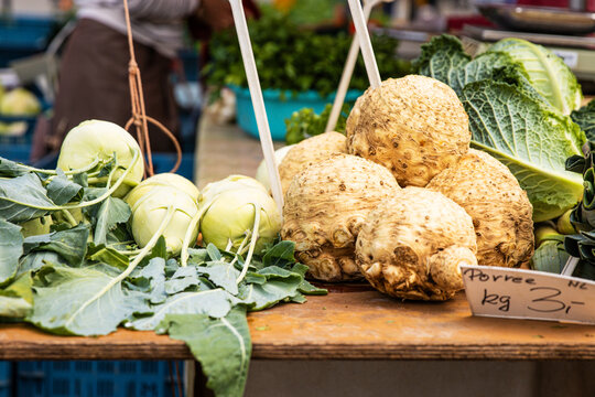 Closeup of fresh kohlrabi and celery root on a wooden table at a local farmer food market. Heap of freshly harvested kohlrabies and celeries.  German turnip. Healthy lifestyle concept.
