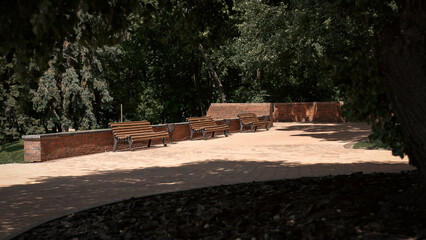 Fototapeta premium Hidden in a quiet corner, benches sit under the shade of trees. This spot offers a tranquil space away from the main paths.