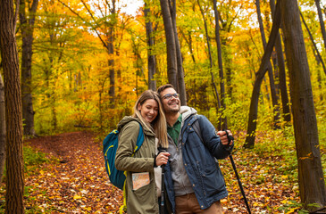 Fototapeta premium Smiling couple with backpacks hiking together in forest.